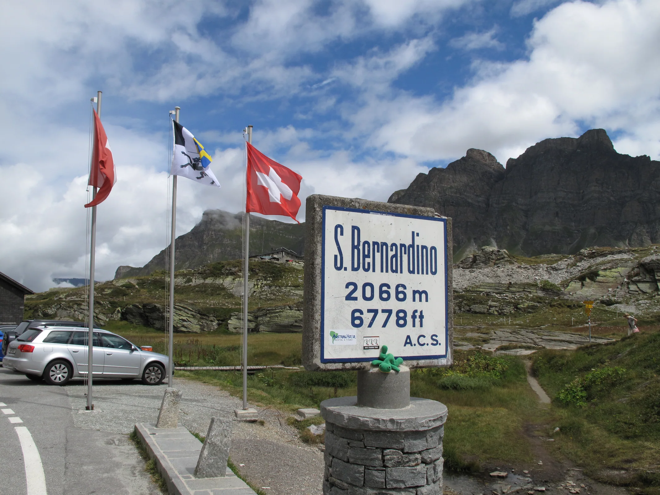 Passschild auf der Höhe des San-Bernardino-Passes vor felsiger Bergkulisse